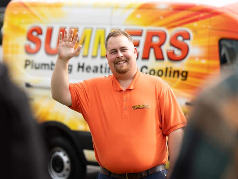 Summers PHC technician waving in front of a branded service van