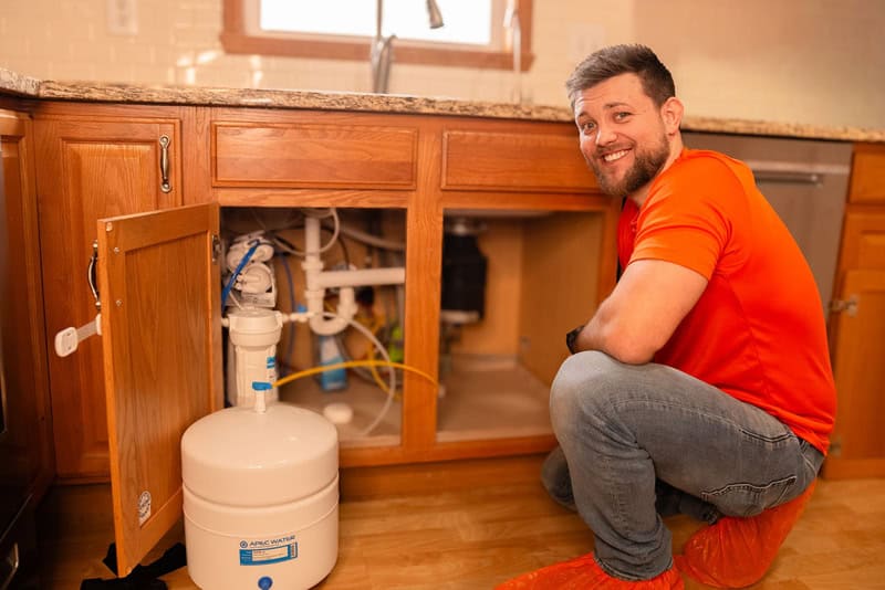 Summers PHC plumber servicing an under-sink water filtration system in a Bloomington-Normal home
